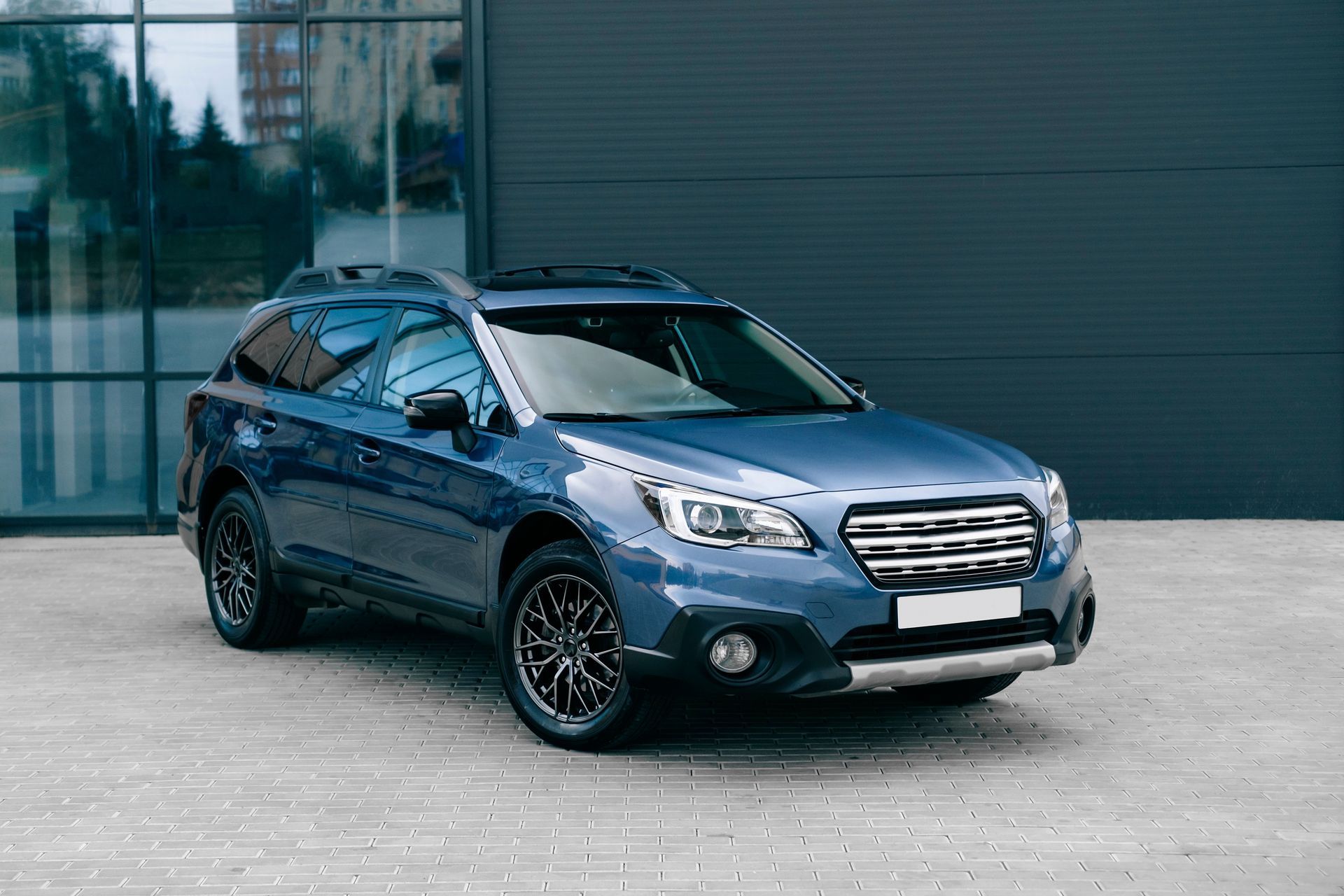 Blue SUV parked in front of a modern building with a glass facade