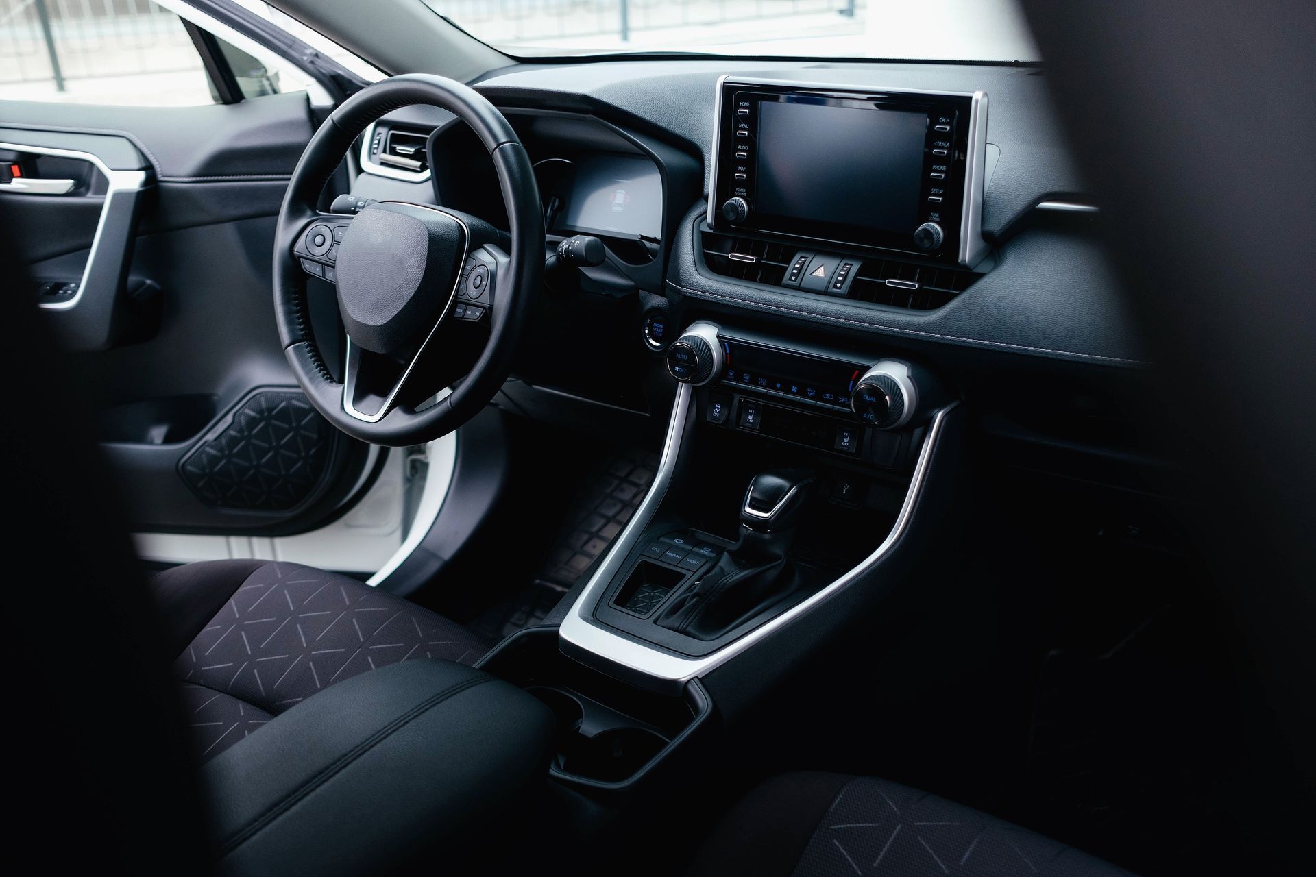 Modern car interior with black seats, steering wheel, center console, and dashboard display
