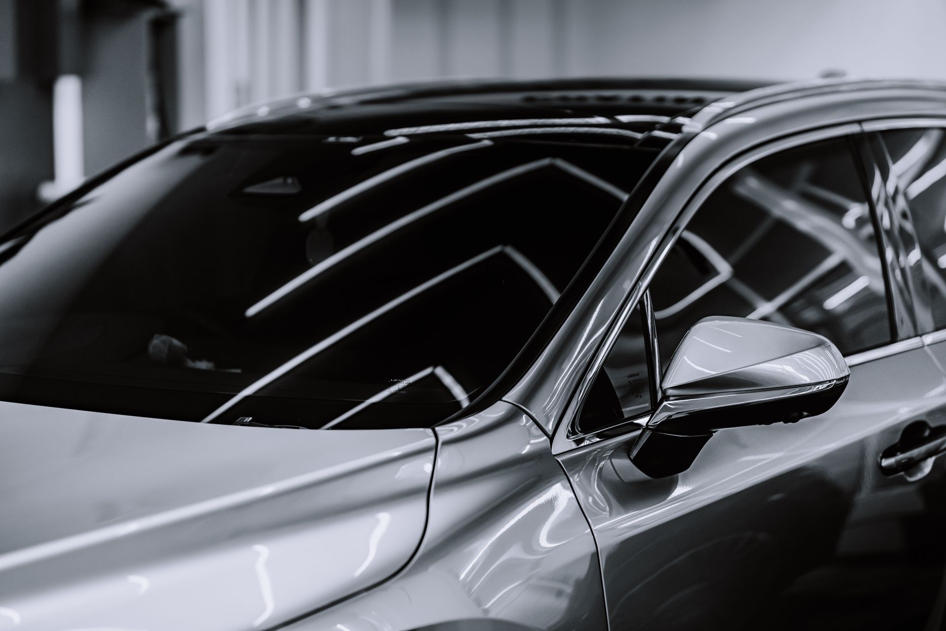 Glossy black sports car in a showroom with bright reflections on the windows and body.