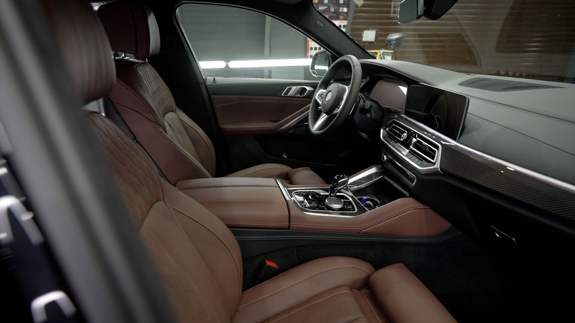 Luxury car interior with brown leather seats, dashboard, and center console in a dark cabin