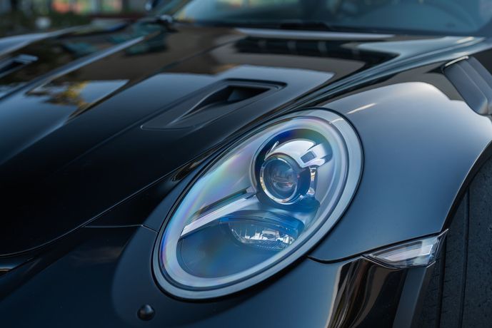 Close-up of a glossy black sports car headlight and hood detail