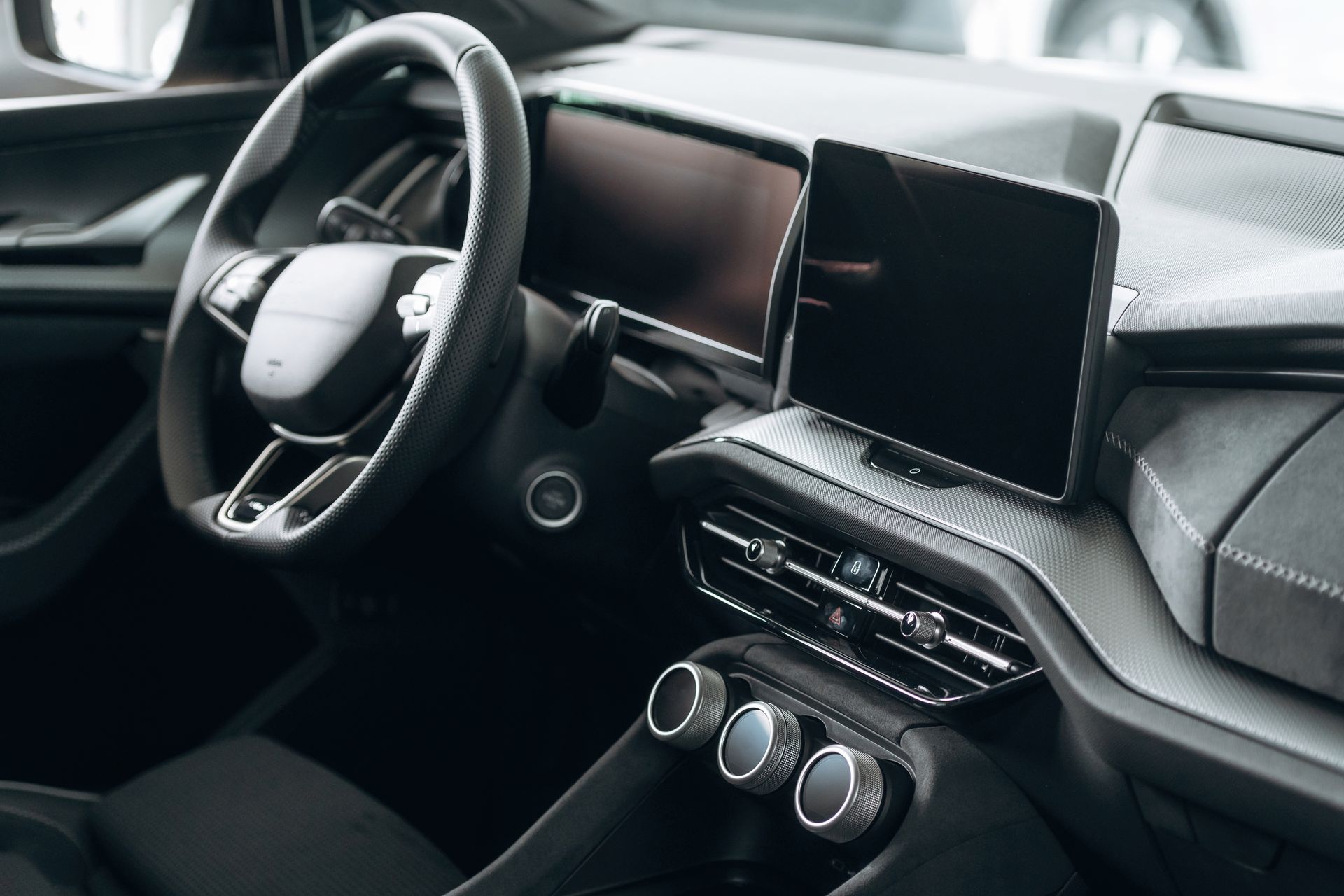 Car interior with a steering wheel, dashboard controls, and a center touchscreen display