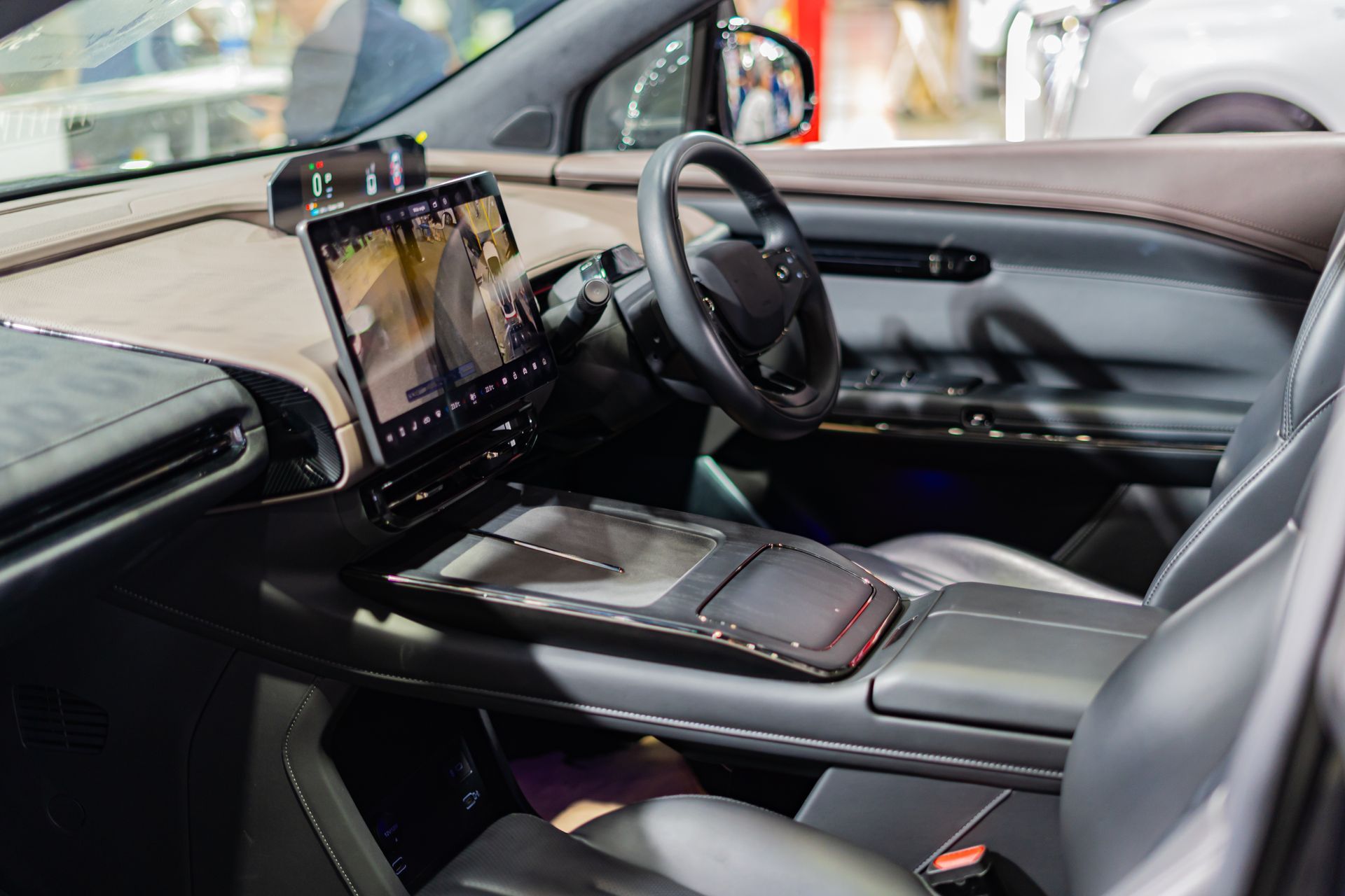 Sports car interior with black leather seats, steering wheel, and a mounted touchscreen display