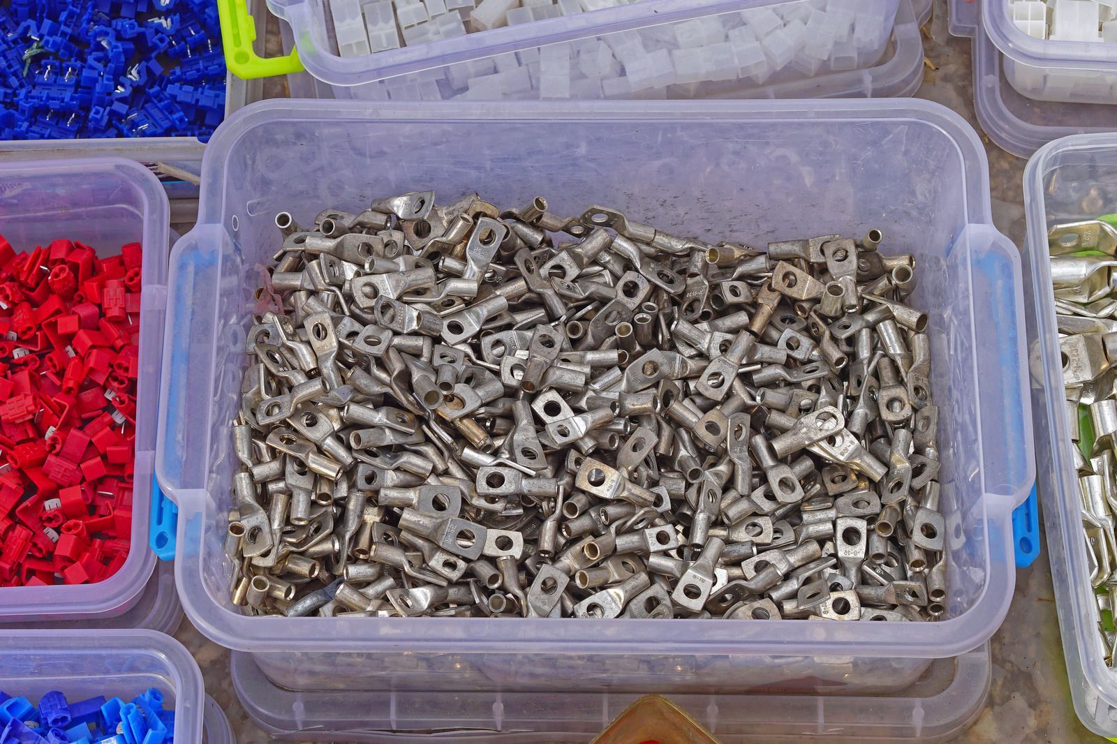 Plastic bins filled with small metal hardware parts in a market-style display