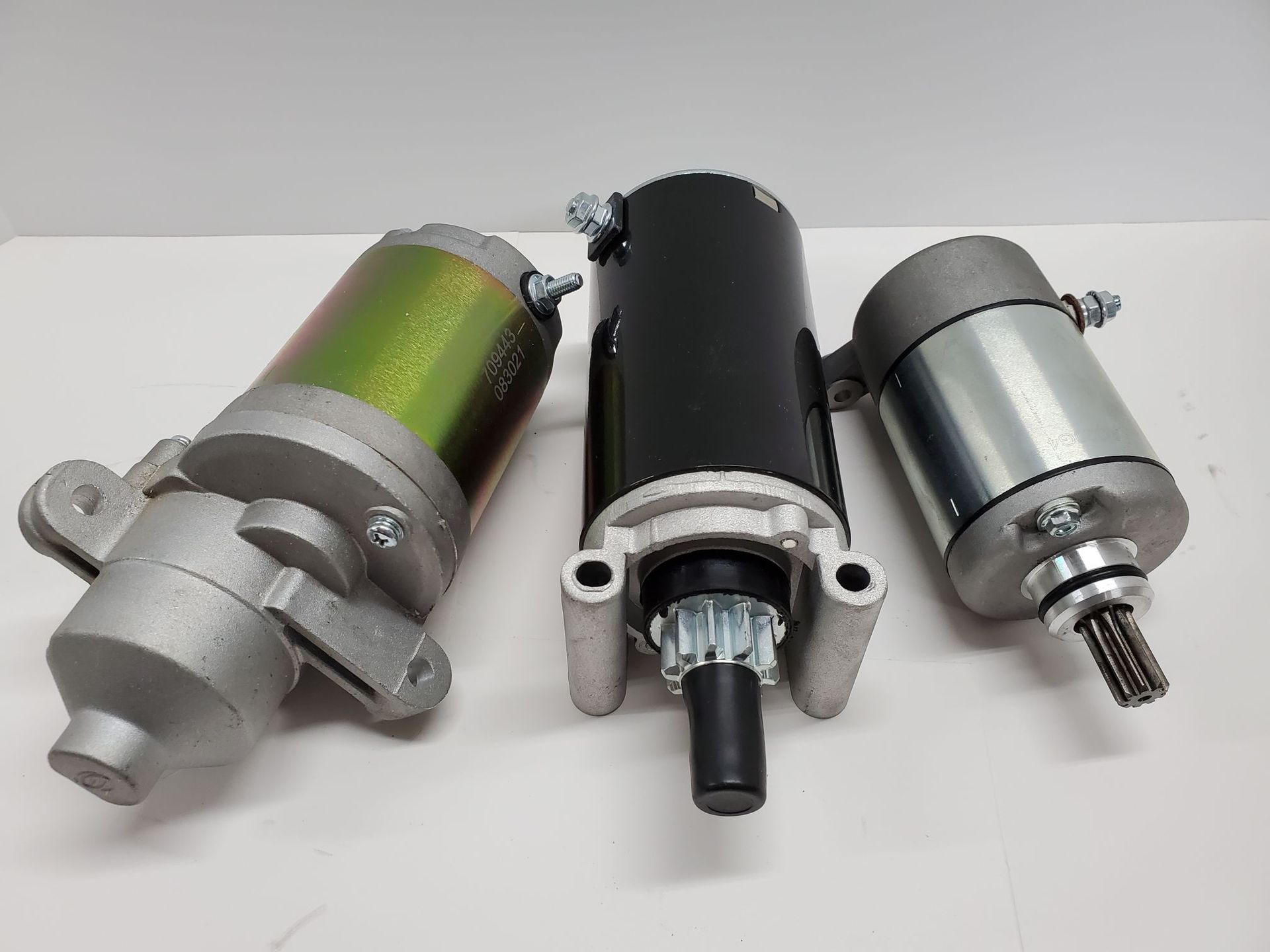 Three small electric motors with metal shafts, shown side by side on a white background