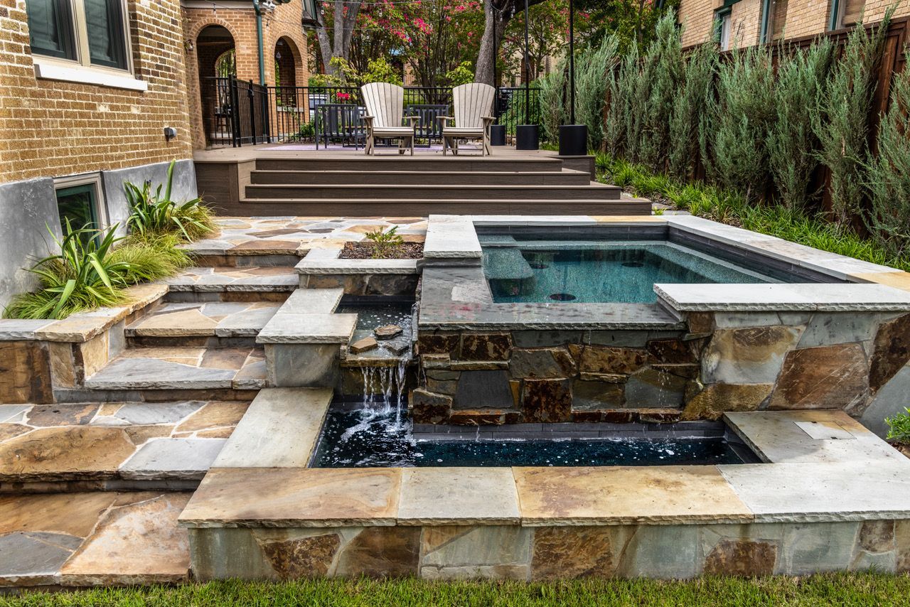 Stone-lined backyard with tiered spa and waterfall. 