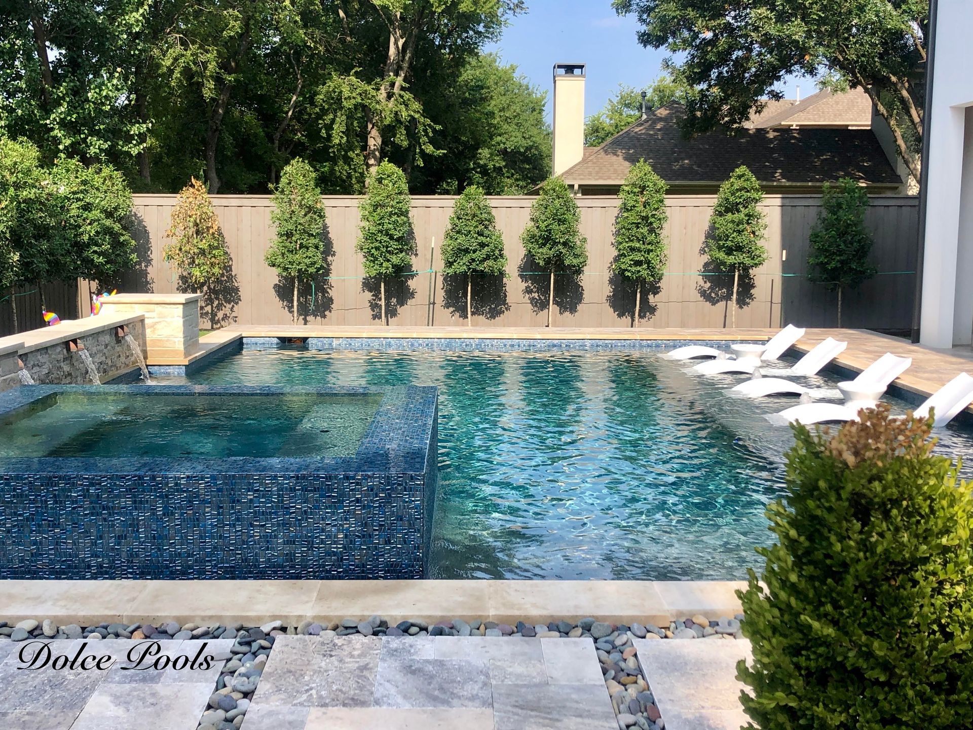 backyard pool with trees and chaise lounges