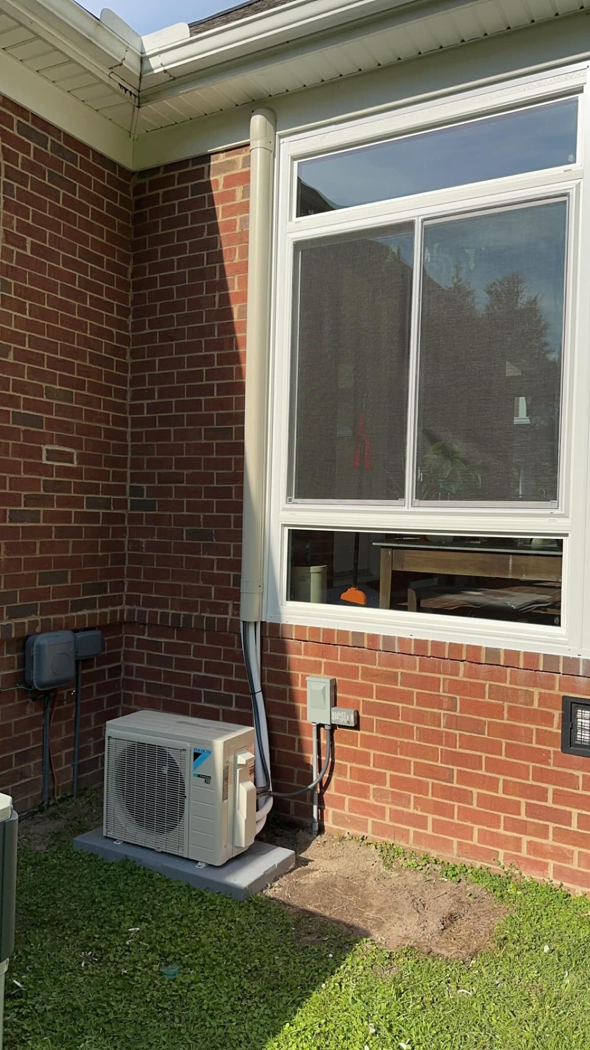 A brick house with a window and an air conditioner on the side of it.