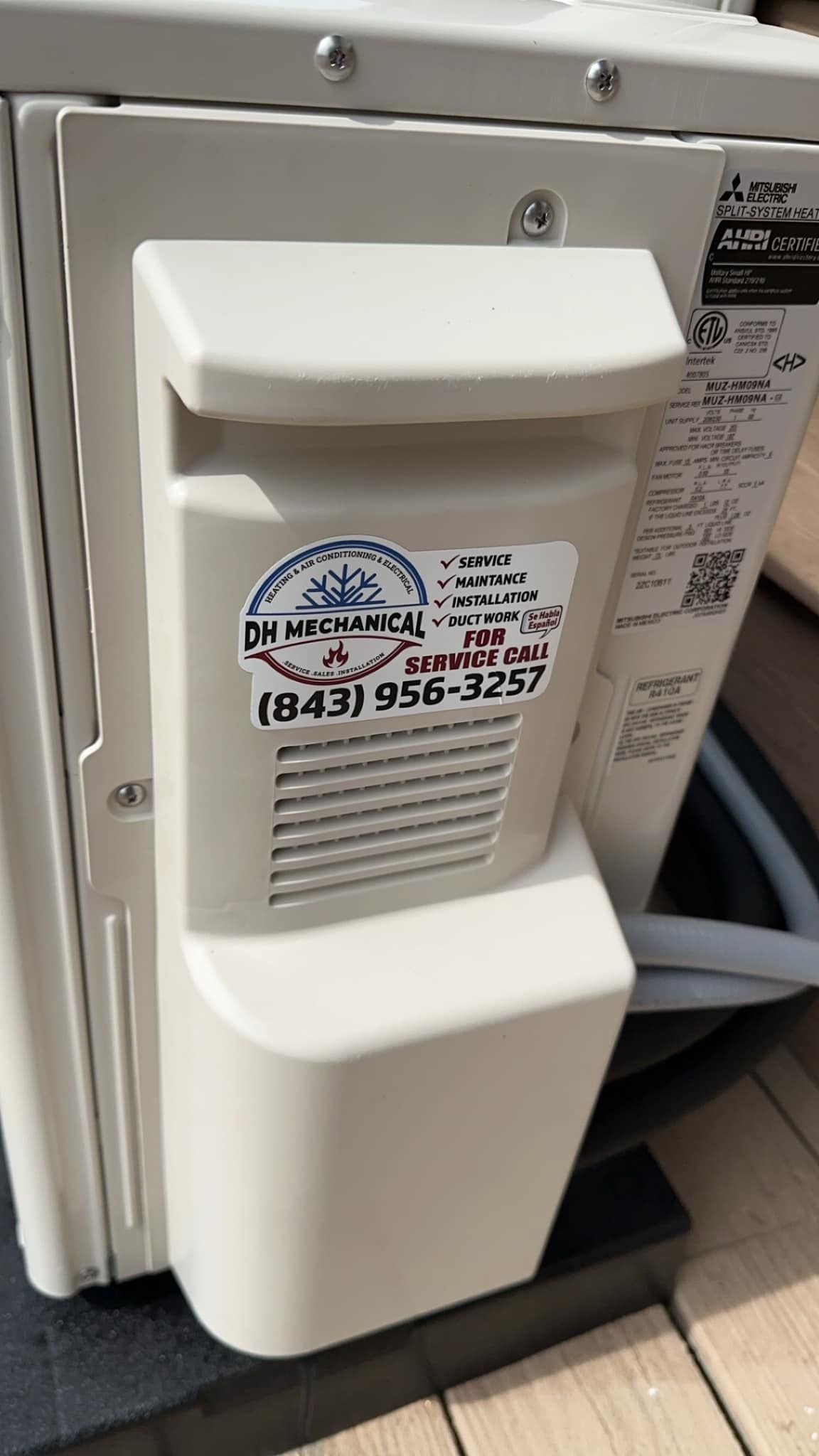 The back of a white air conditioner with a sticker on it.