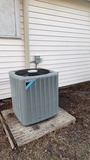 An air conditioner is sitting on the side of a house.
