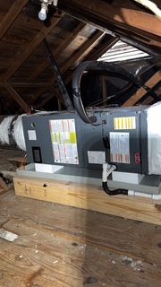 An air conditioner is sitting in the attic of a house.