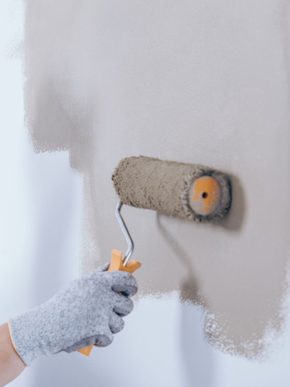 A person is painting a wall with a paint roller.