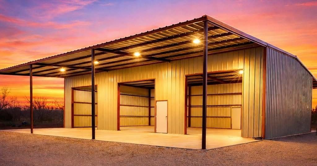 Open-sided metal barn at sunset with warm lights and a gravel foreground