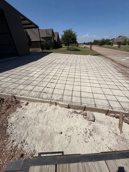Broken sidewalk beside houses and a dirt road on a sunny day