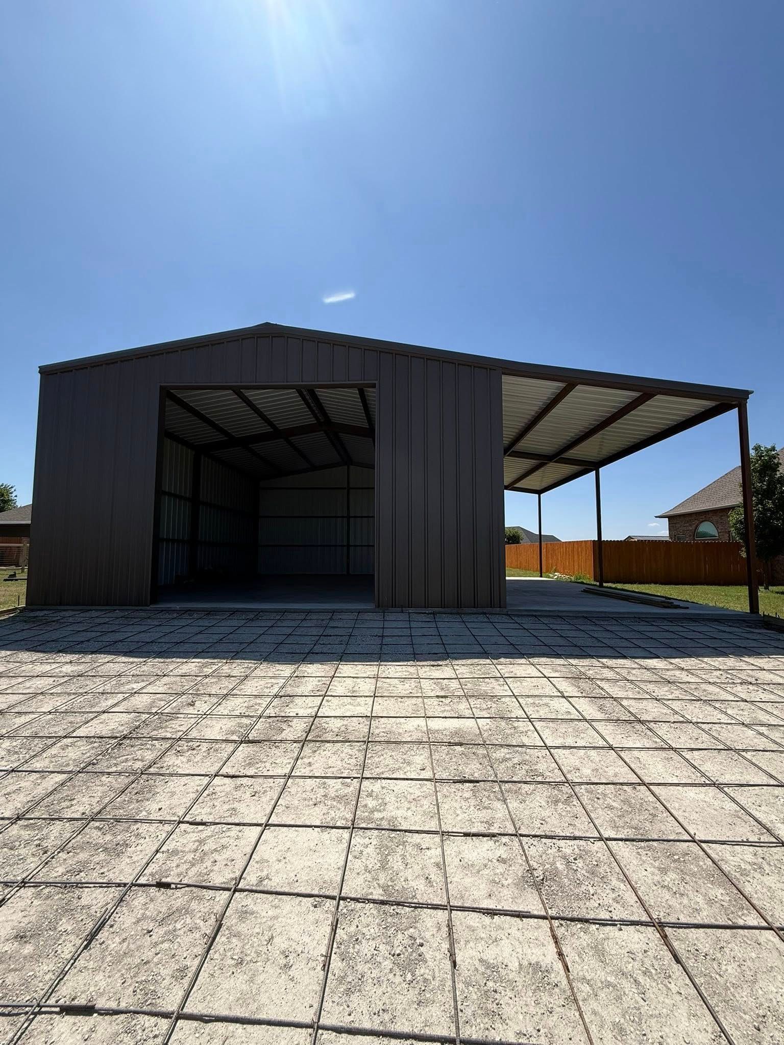 Black metal carport beside a paved lot under a clear blue sky