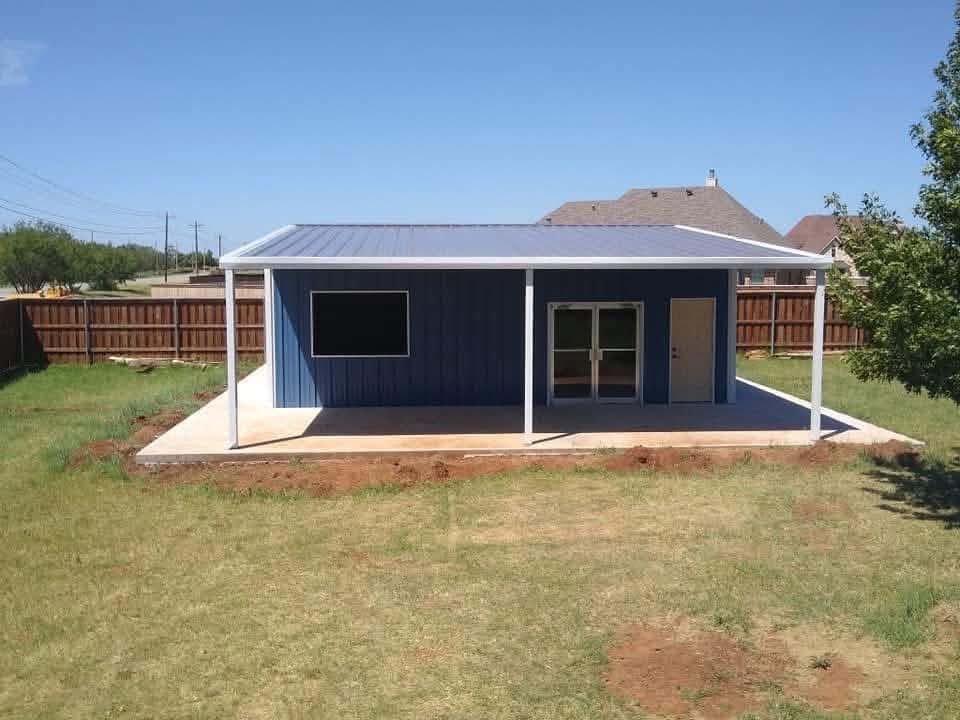 Small blue house with a covered front porch and grassy yard under a clear sky