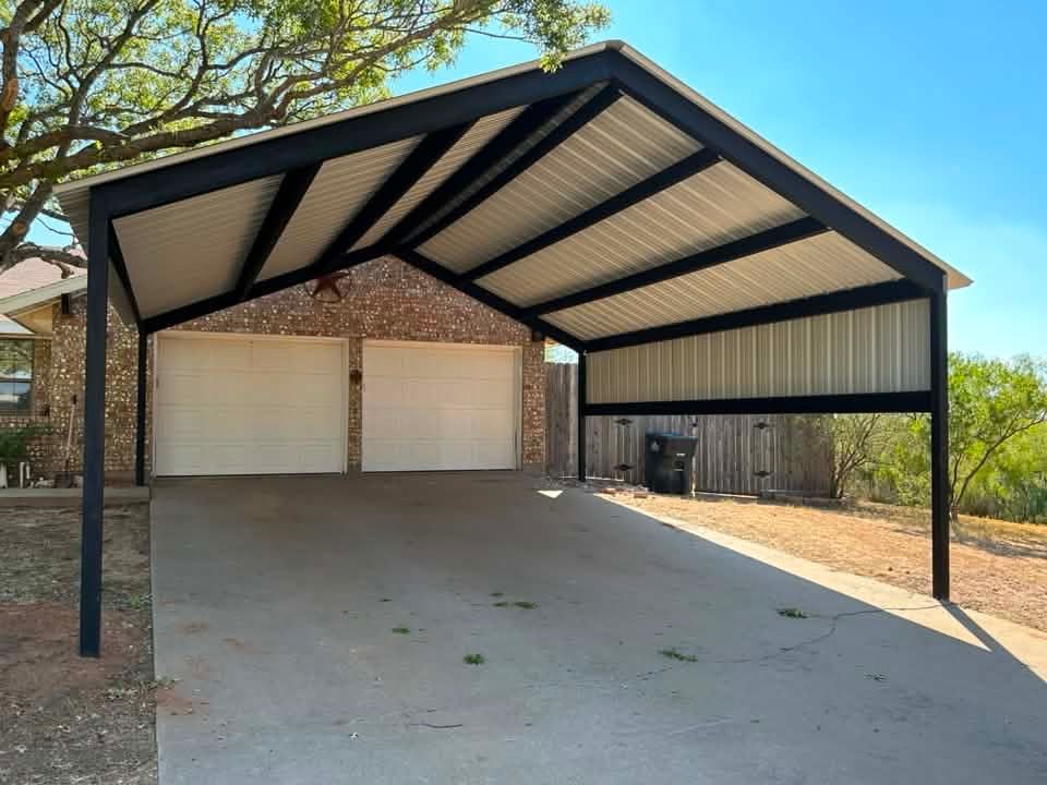 Covered two-car driveway carport with a steep metal roof and brick garage in the background.