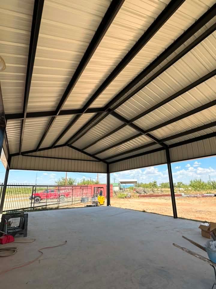 Open-air pavilion with metal roof and concrete floor, overlooking a construction site with equipment and fencing