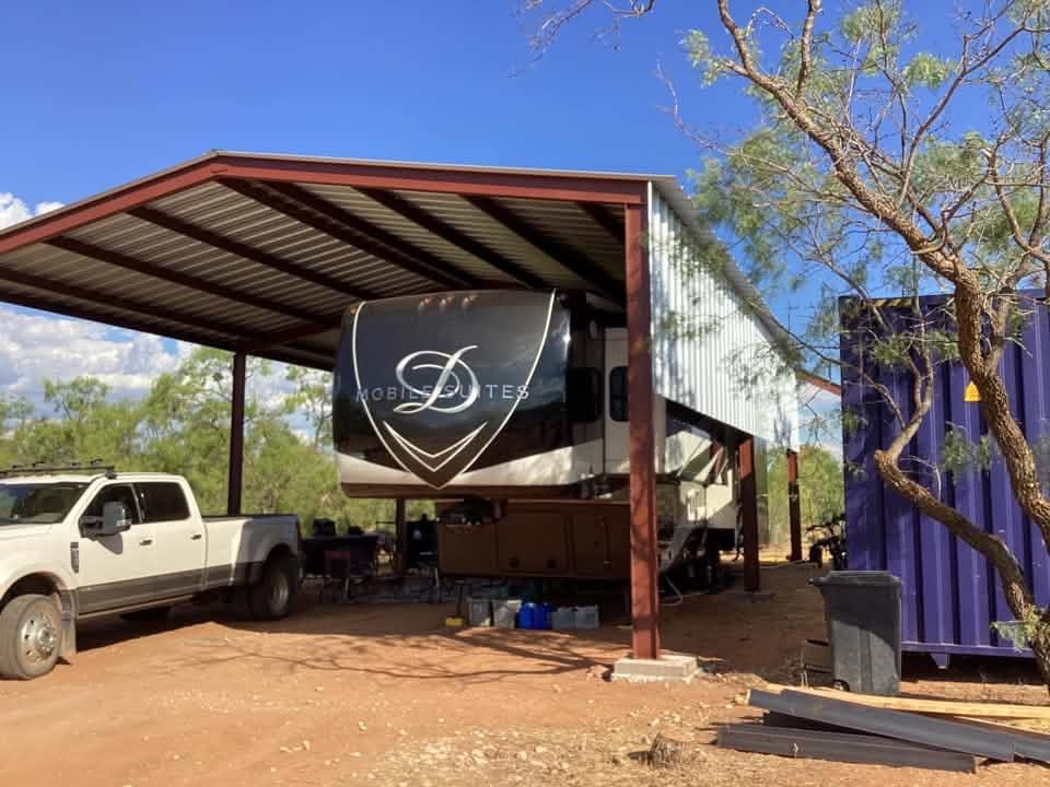 Outdoor metal-roof shed with a white truck parked beside it and a black banner hanging in front