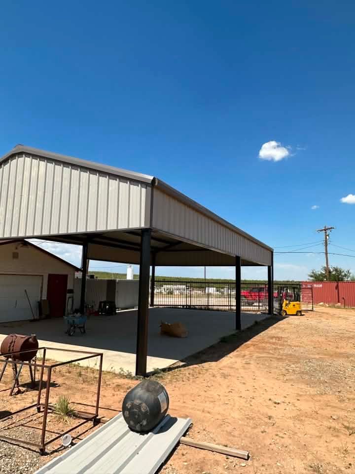 Open-sided metal shed in a dusty yard under a clear blue sky