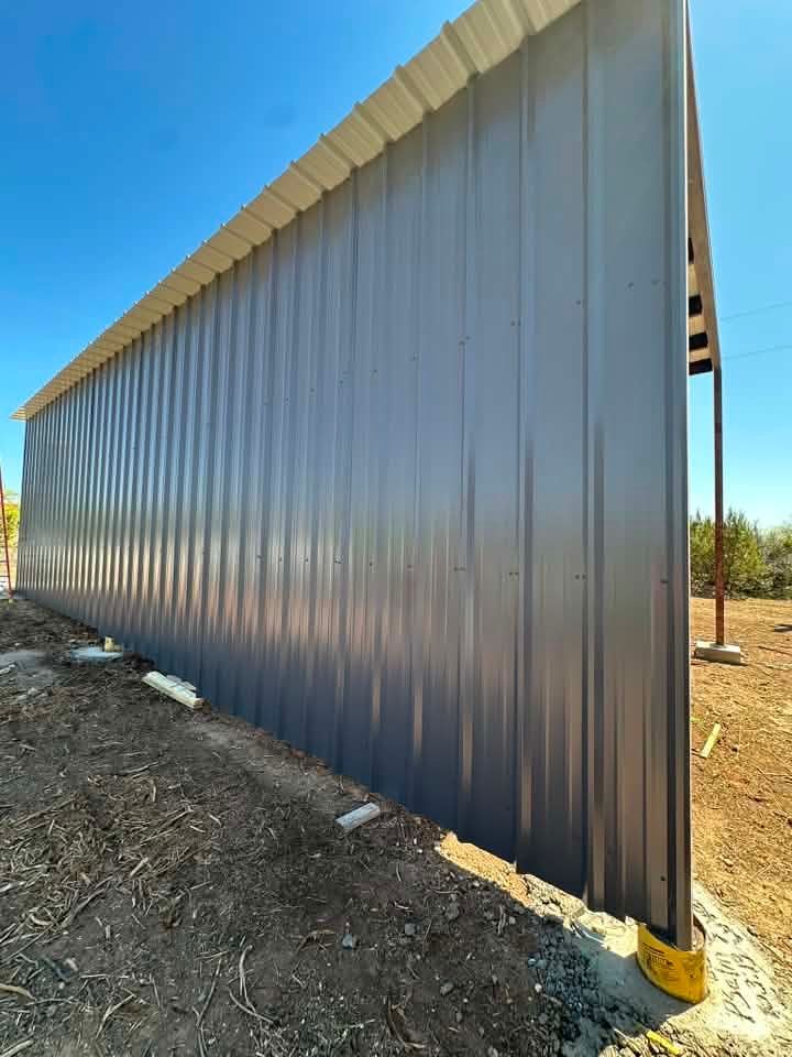 Corrugated metal shed wall with a white top and dark lower panels in a dry, outdoor area