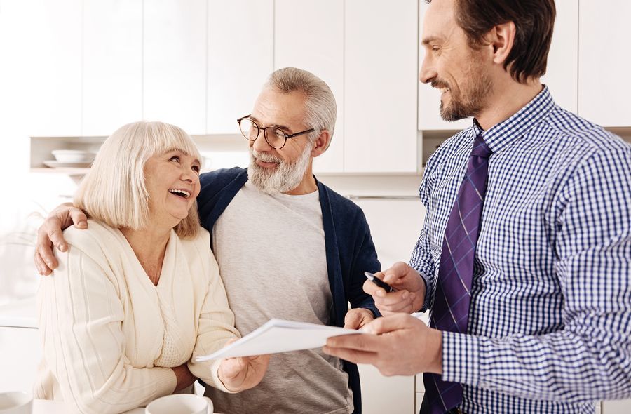 A man is holding a piece of paper in front of two older people.