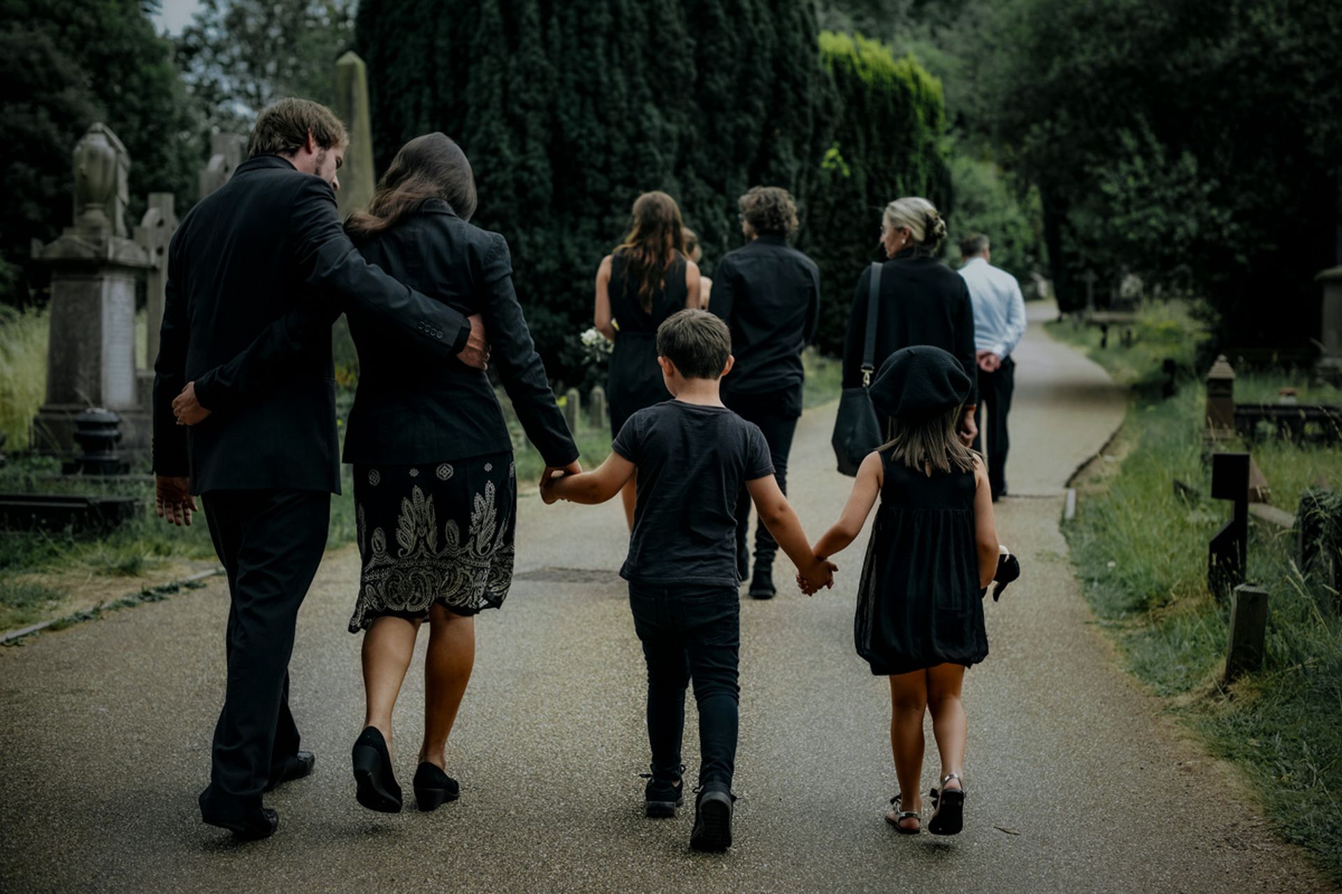 Family walking hand in hand along a tree-lined path in a park