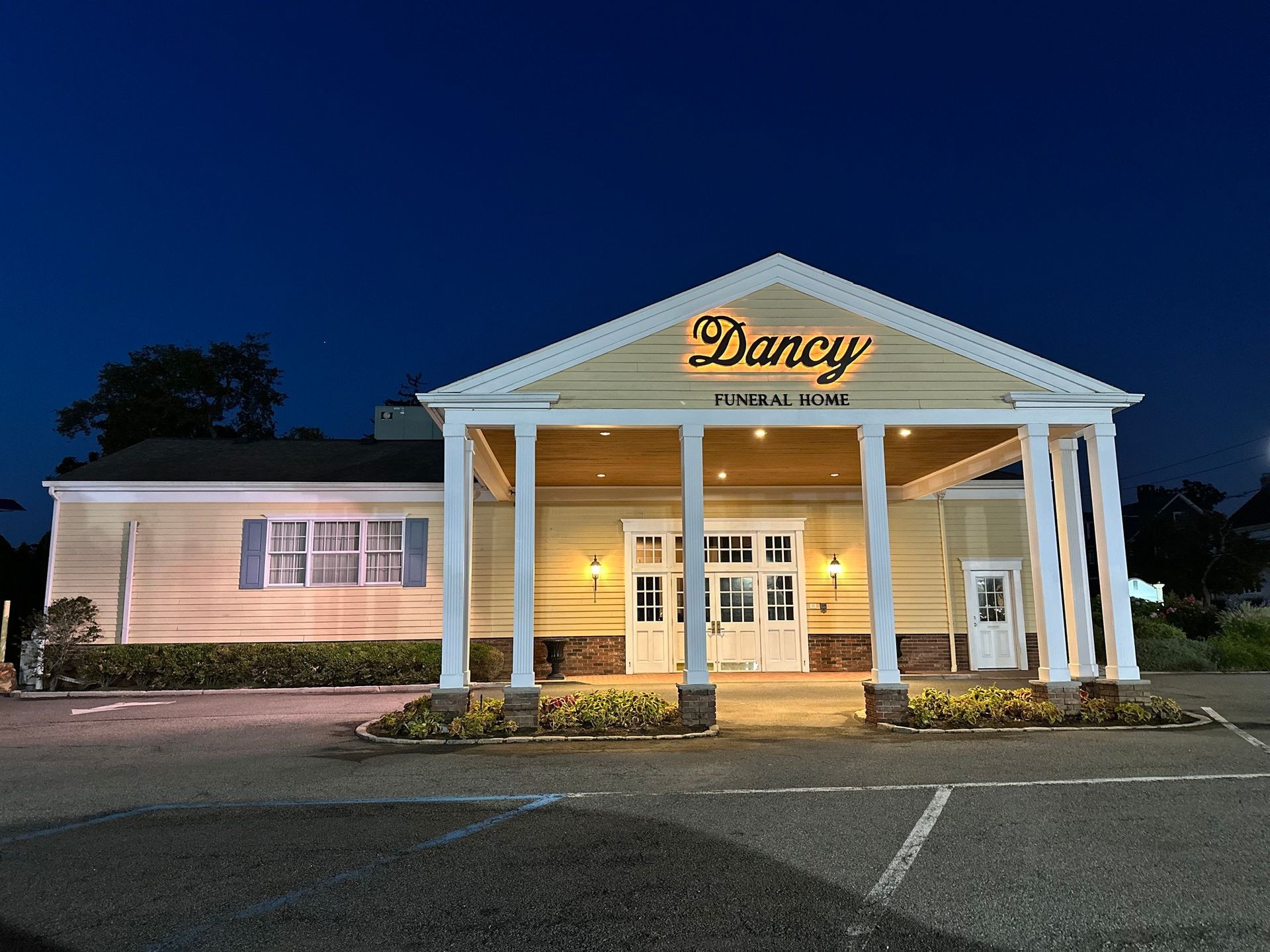 Daisy restaurant at dusk, with white columns and warm lights glowing at the entrance