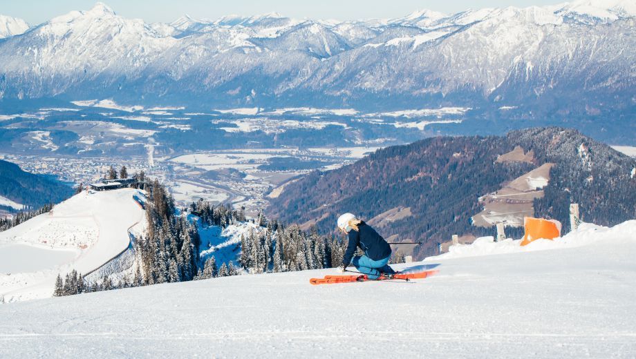 A person is skiing down a snow covered slope with mountains in the background.