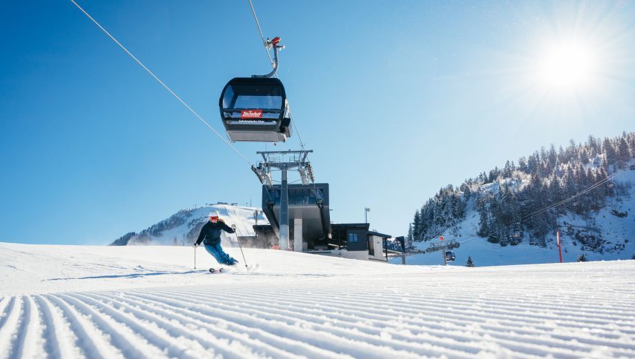 A person is skiing down a snow covered slope next to a ski lift.