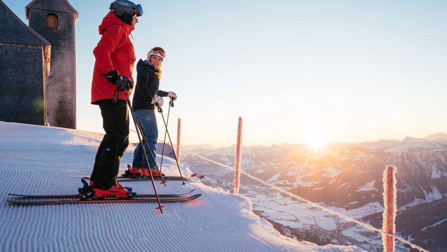 Two people are skiing down a snow covered slope.