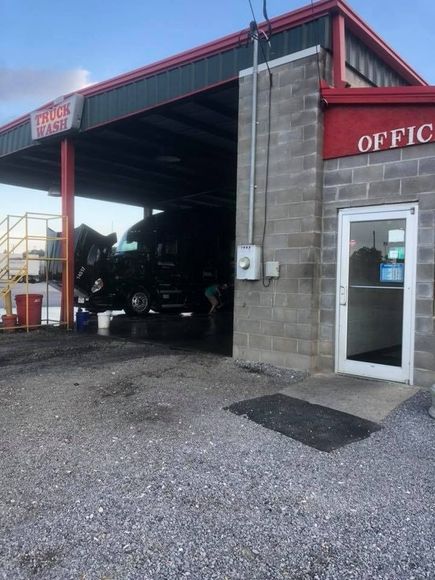 Auto repair shop entrance with a truck inside, gray block wall, and office door on the right