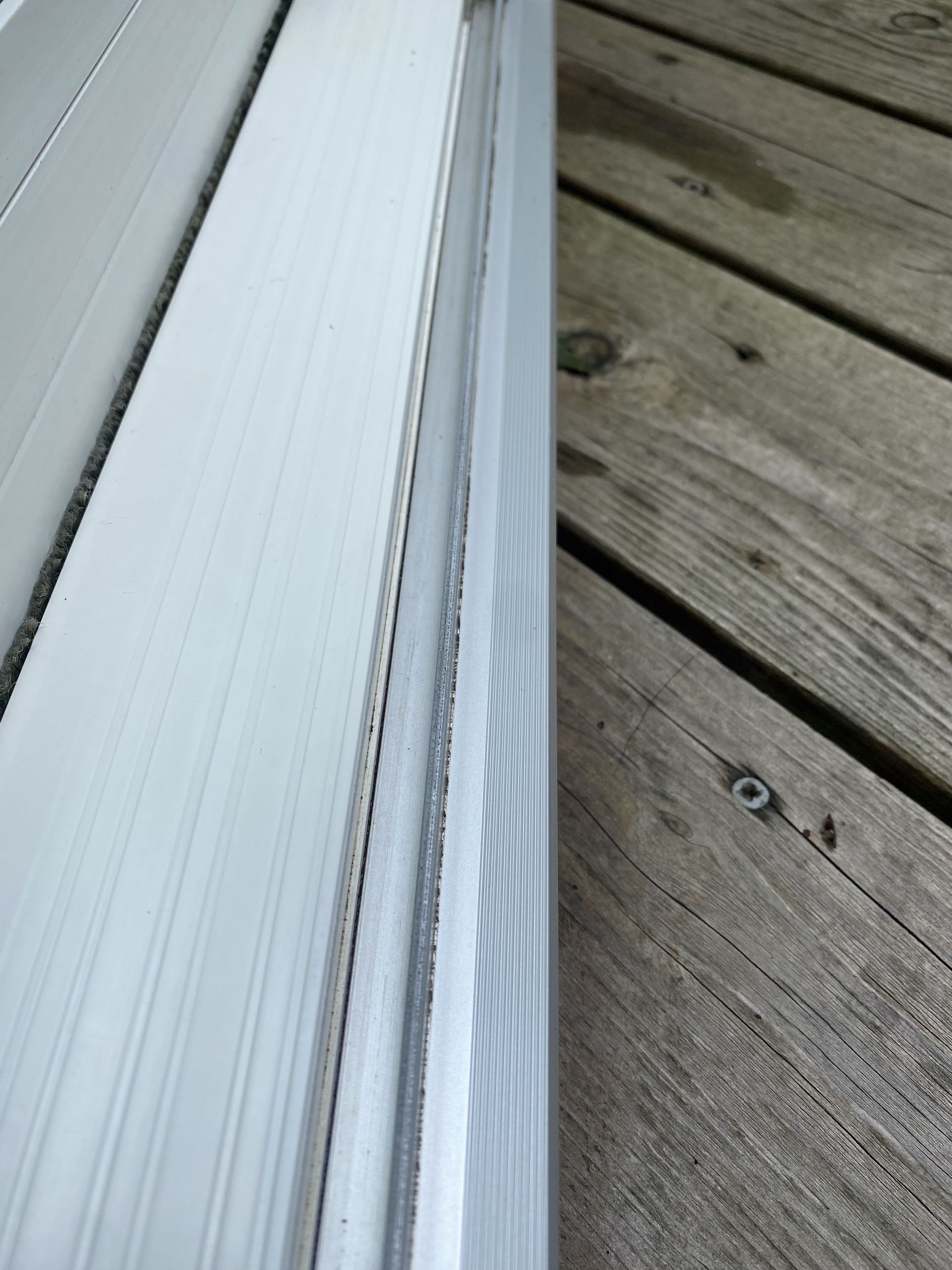 a white window frame is sitting on top of a wooden deck .