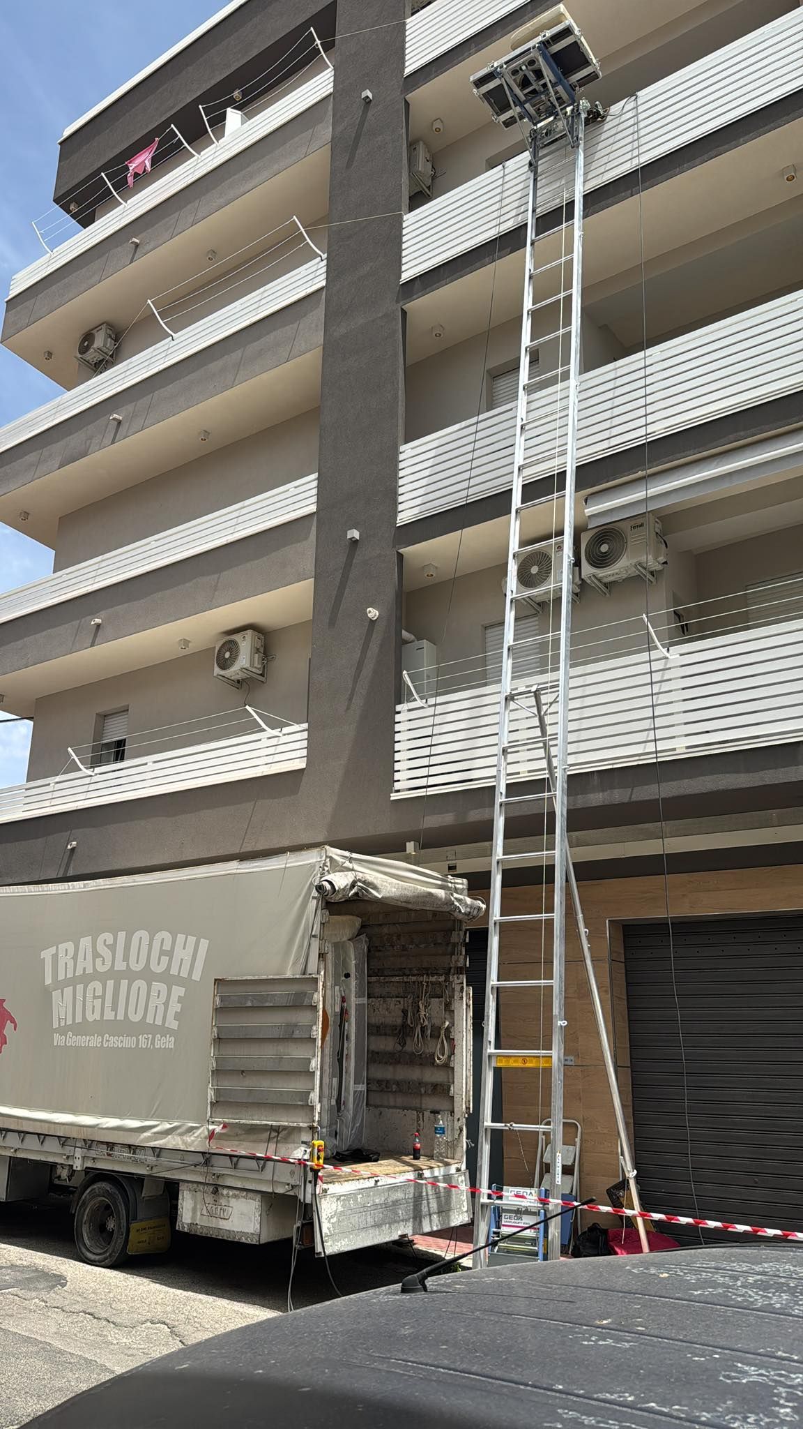Un camion con una scala attaccata è parcheggiato davanti a un edificio.