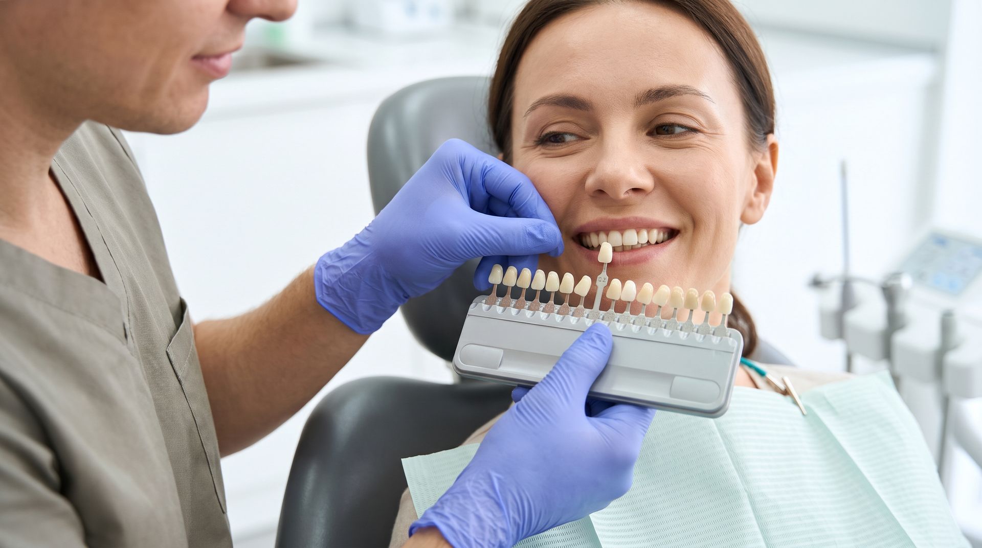 Dentist showing tooth shades to a smiling patient in a dental exam chair