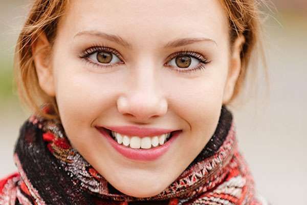 A close up of a woman 's face wearing a scarf and smiling.