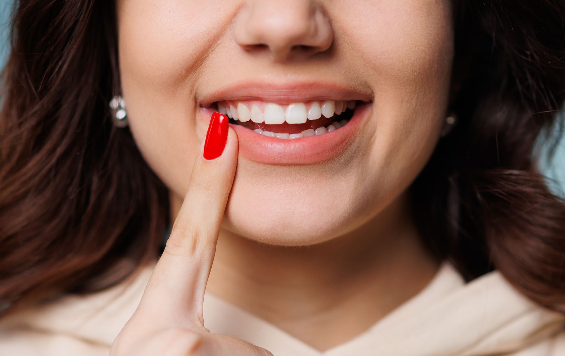Close-up of a smiling mouth with a finger pointing to a chipped front tooth