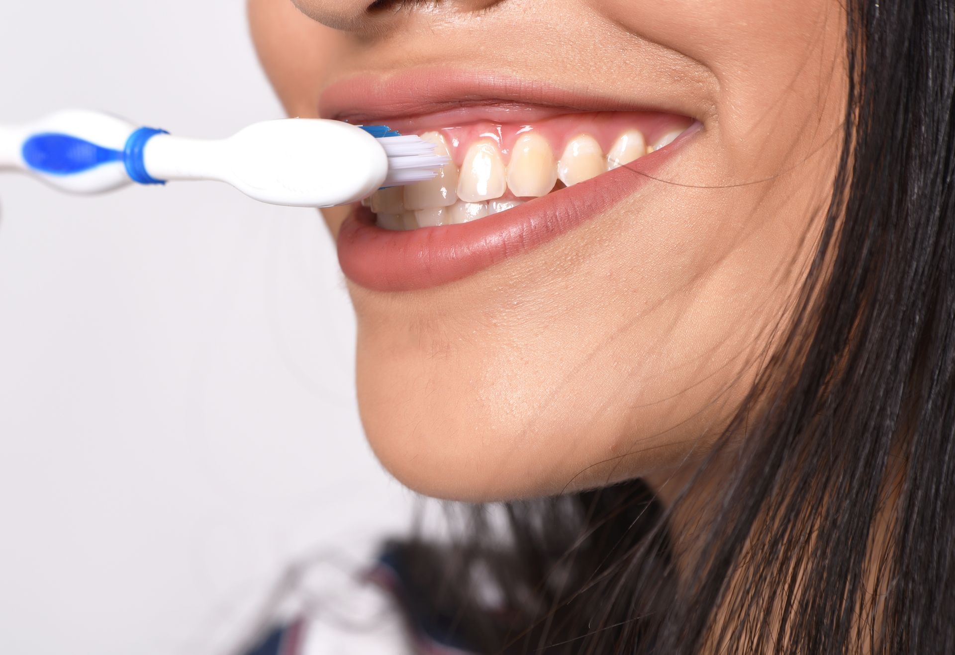 Person brushing their teeth with a blue-and-white electric toothbrush close-up