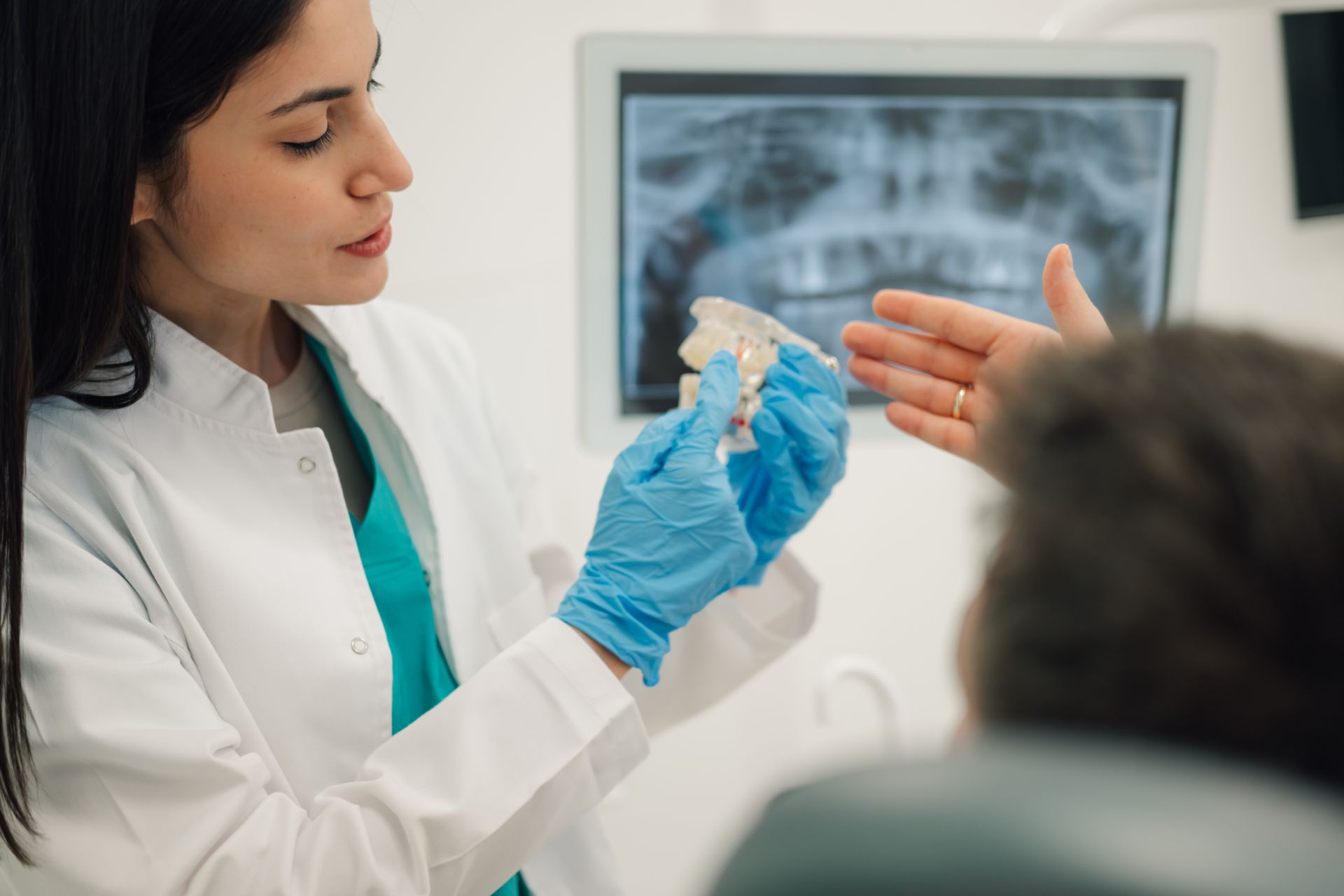 Dentist in a white coat shows a dental mold to a patient in a clinic