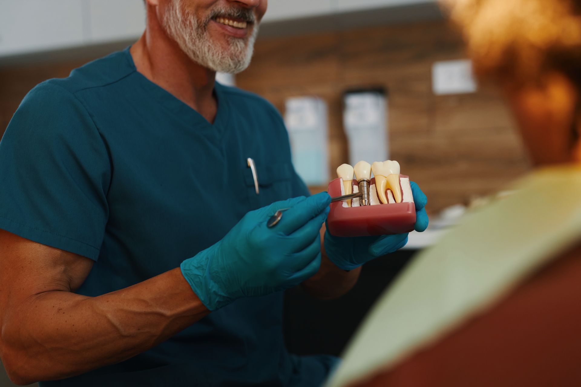 Dentist pointing at a tooth model while explaining to a patient.
