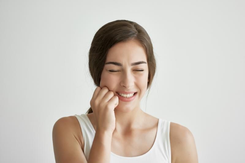 A woman is holding her hand to her face because she has a toothache.