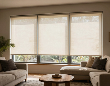 Sala de estar moderna con grandes ventanales, sofás beige y una mesa de centro redonda de madera