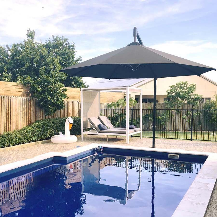 A Swimming Pool With a Black Umbrella and a Swan Float — Cover Me NQ in Currajong, QLD