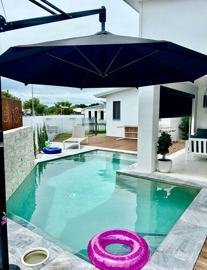 A Large Swimming Pool With a Large Umbrella Over It — Cover Me NQ in Currajong, QLD