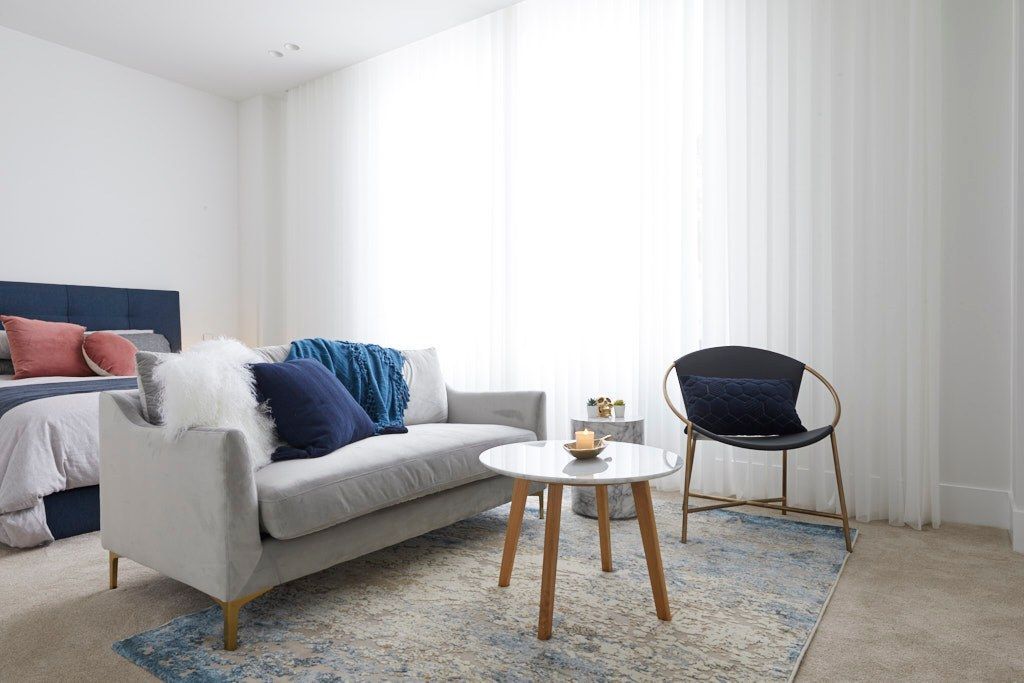 A Living Room With a Green Couch and White Curtains — Cover Me NQ in Currajong, QLD