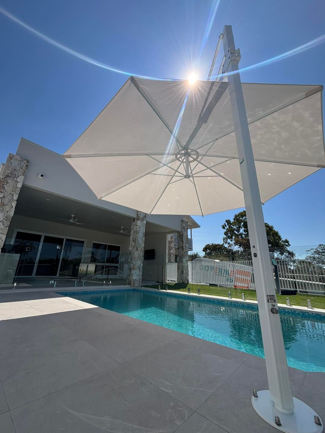 A Black Umbrella is Sitting Next to a Large Swimming Pool — Cover Me NQ in Currajong, QLD