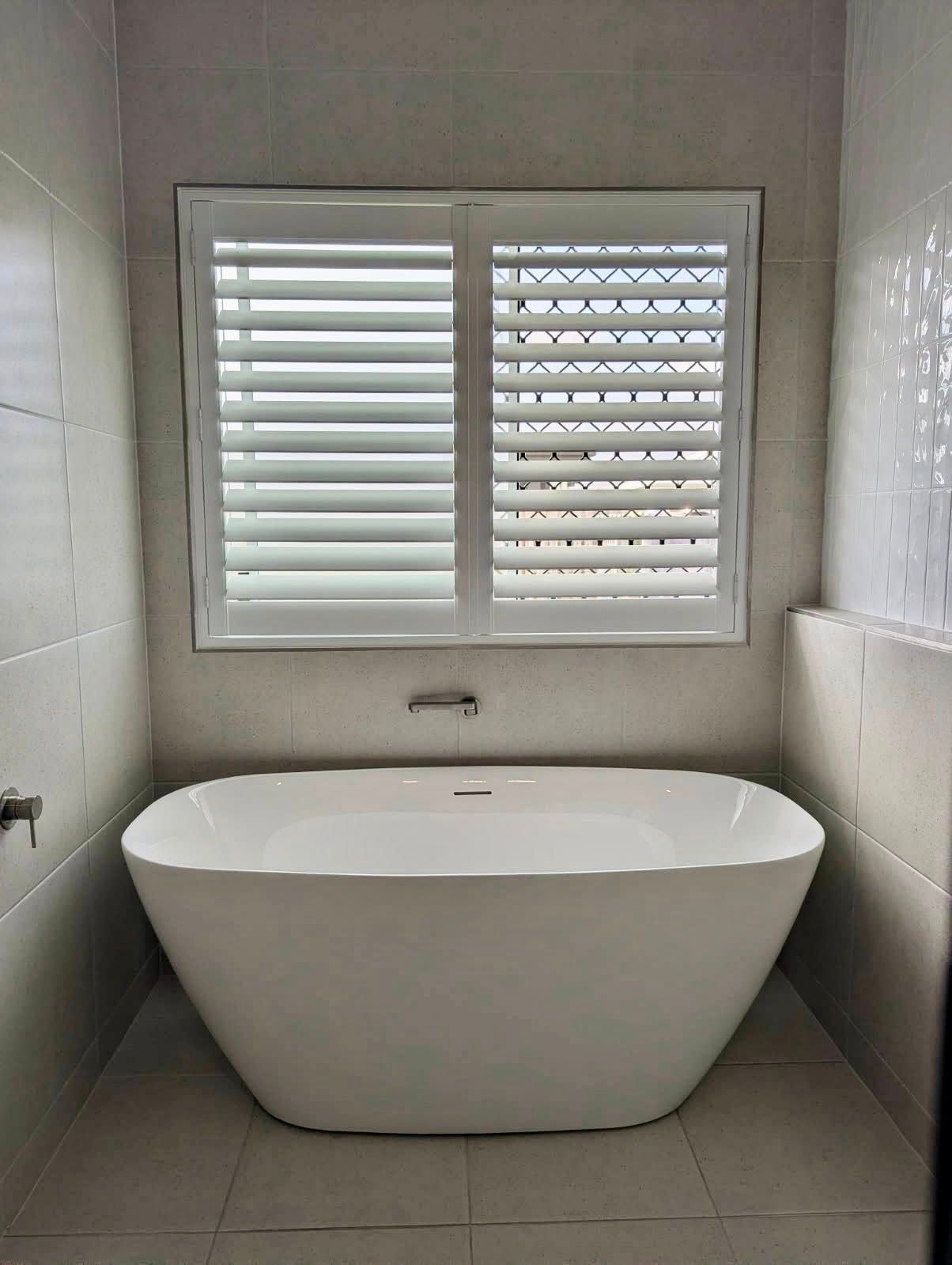 A Bathroom With a Bathtub and a Window With Shutters — Cover Me NQ in Currajong, QLD