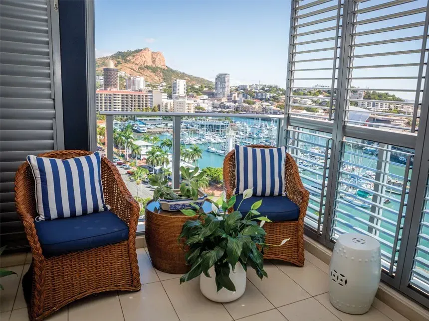 There Are Two Chairs and a Table on the Balcony With a View of the City — Cover Me NQ in Currajong, QLD