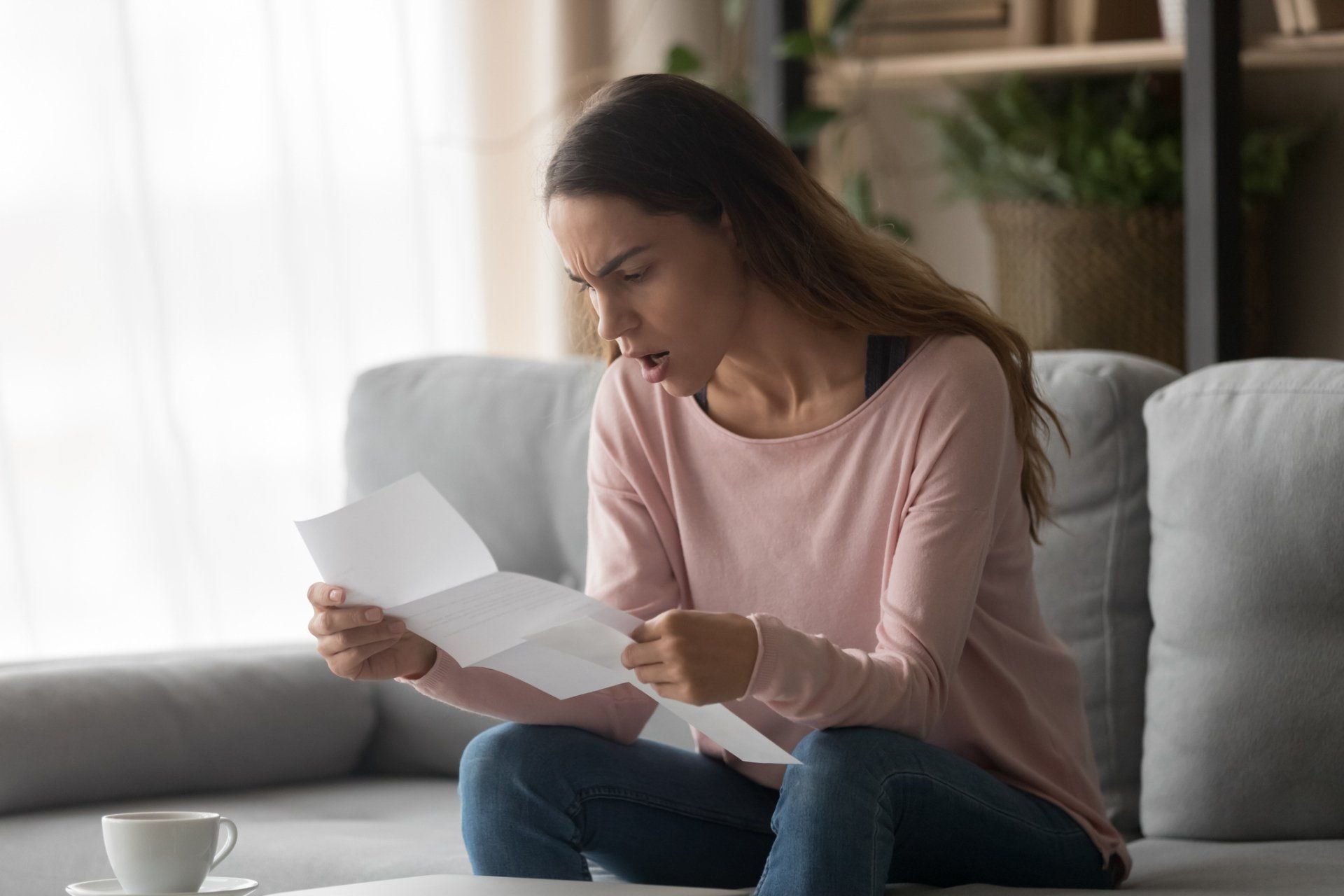 Woman Sitting On Couch Holding High Utility Bill — Concord, NC — Faithful Appliance Repair