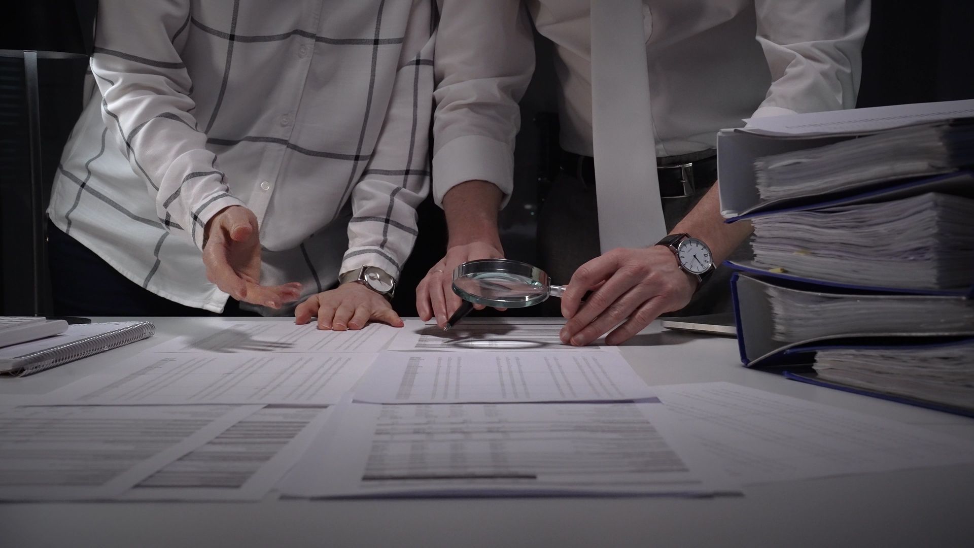 Two business people inspect documents for fraud.